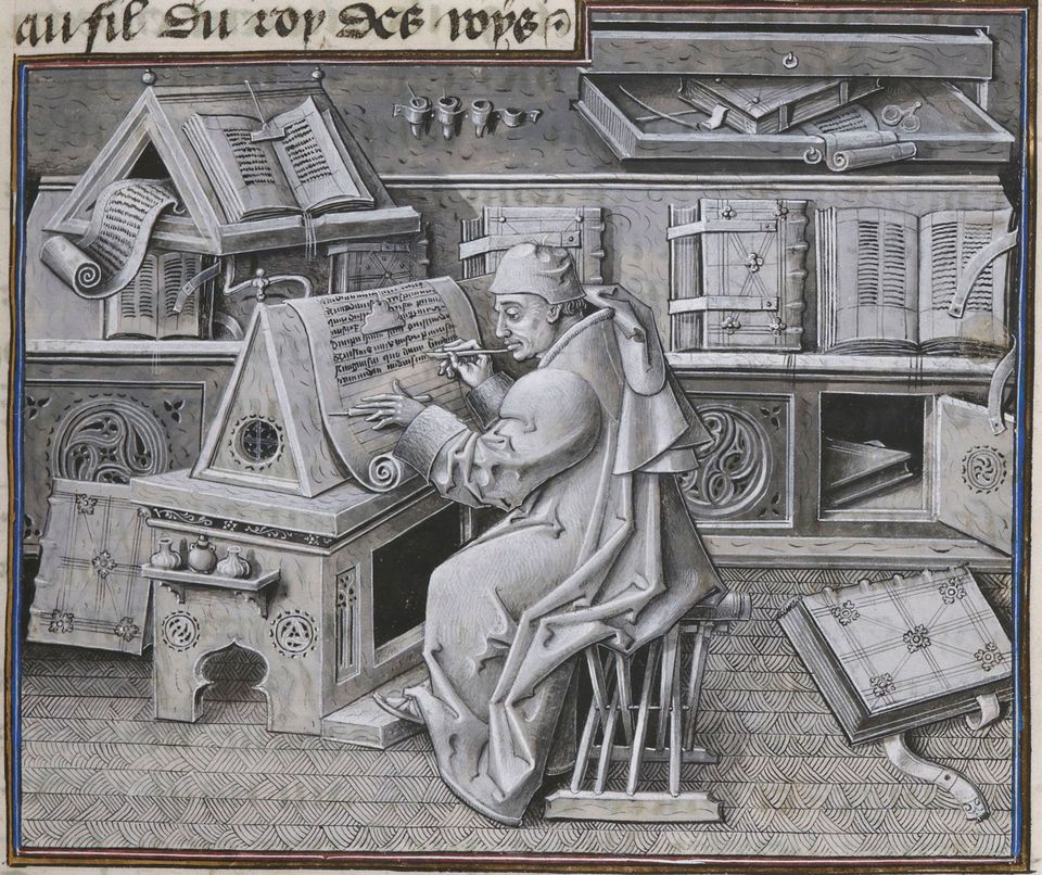 A medieval scribe at his writing desk surrounded by books.