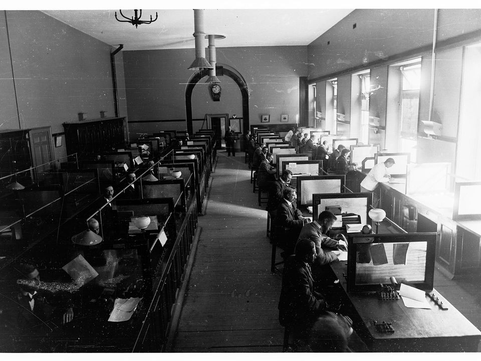 Rows of men at telegraph desks in a post office.